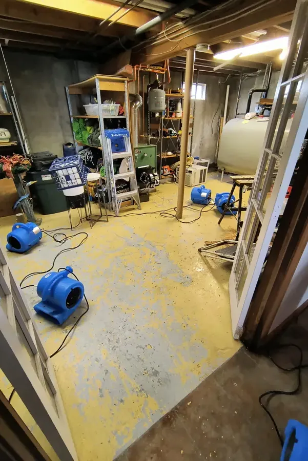 Air movers drying a wet lower-level workshop floor