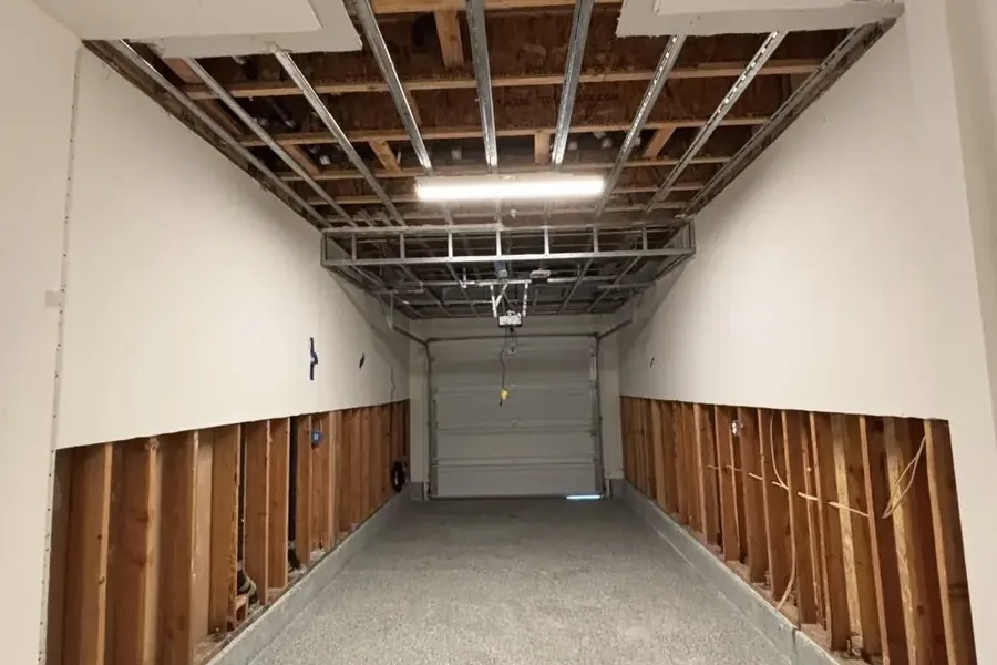 Garage with drywall flood cuts along both walls after a tank leak