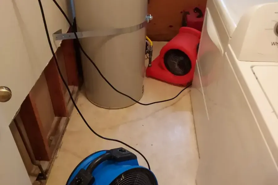 Air movers drying a laundry area with the wall opened behind the washer