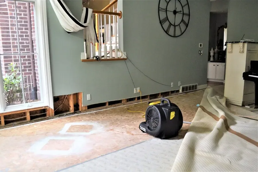 Restoration crew setting up drying equipment inside a water damaged home