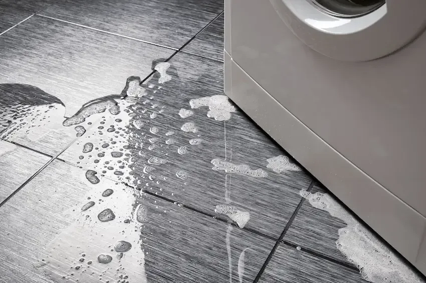 Water spreading over tile beside a leaking washing machine