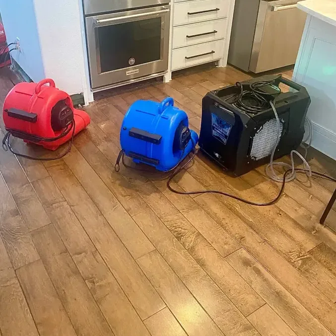 Air movers and a dehumidifier drying a wood kitchen floor